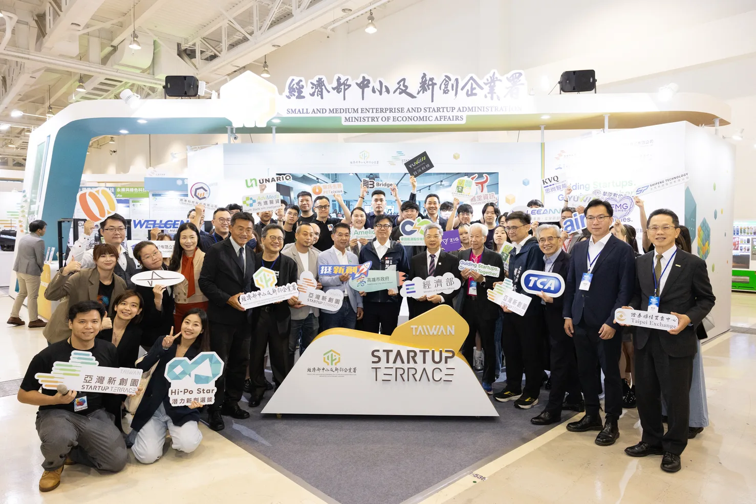2026 Meet Greater South 經濟部中小及新創企業署主題館大合照,優那科創與各領域新創團隊、政府代表共同入鏡,前方為亞灣新創園 Startup Terrace 主視覺