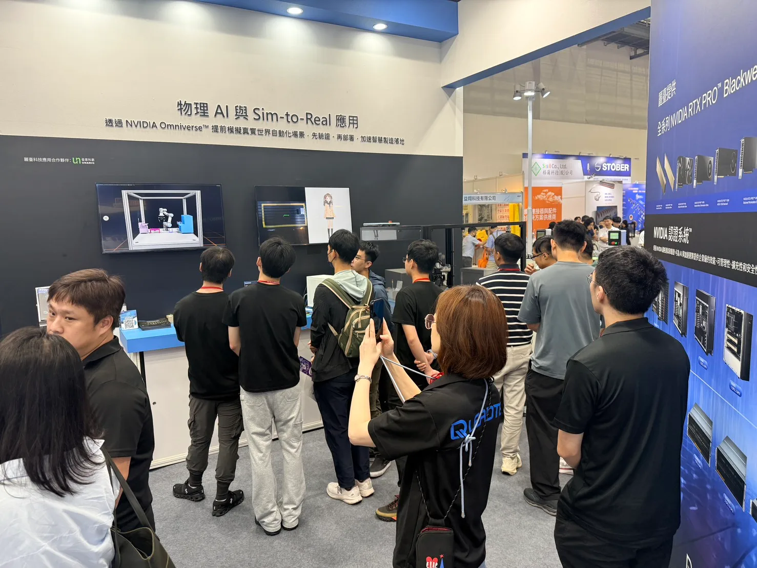 參觀者聚集在寫著「物理 AI 與 Sim-to-Real 應用」的攤位主視覺牆前,觀看螢幕上的 NVIDIA Omniverse 機器人模擬畫面,牆面標示麗臺科技應用合作夥伴為優那科創